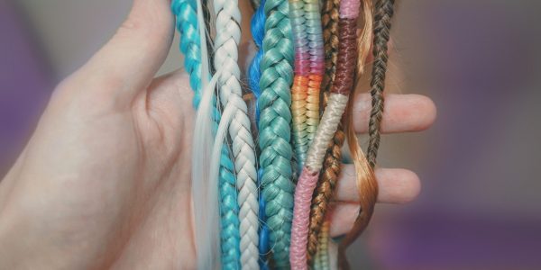 learning to weave braids on a mannequin, weaving different harnesses from colored kanekalon